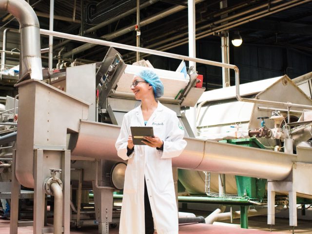 Femme en usine avec une blouse Bonduelle et une tablette