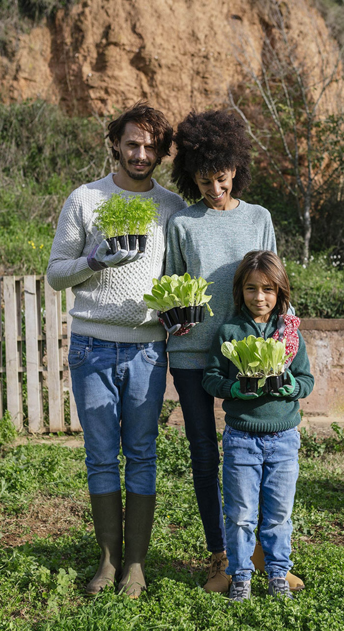 Famille de trois personnes avec des plants dans les mains